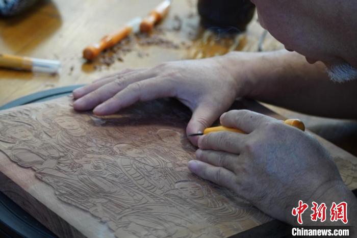 圖為徐晉林湊近木板，近距離制作雕版畫(huà)?！【琶赖┰?　攝