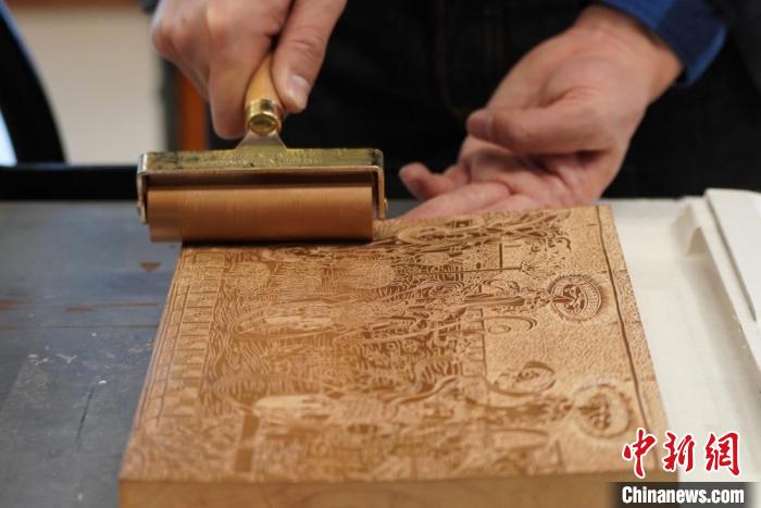 圖為徐晉林工作室工作人員正在給雕好壁畫(huà)的版面滾油墨?！【琶赖┰?　攝