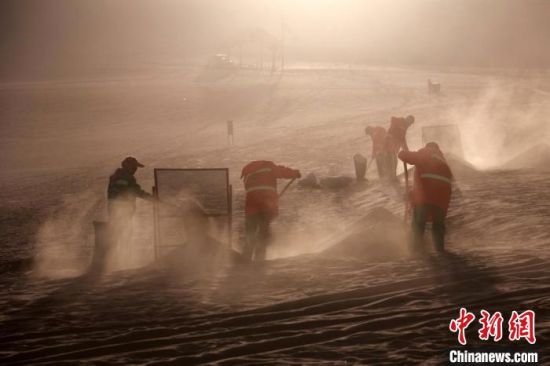 圖為敦煌市鳴沙山月牙泉景區(qū)“駱駝保姆”清理駱駝糞便?！垥粤?攝