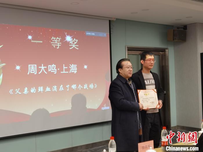 圖為作家、西北師范大學(xué)新聞與傳媒學(xué)院院長(zhǎng)徐兆壽頒發(fā)一等獎(jiǎng)證書，代領(lǐng)獎(jiǎng)?wù)呱吓_(tái)領(lǐng)獎(jiǎng)?！钅?攝