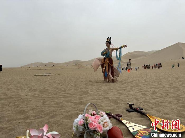 圖為2023年4月底，敦煌大漠“逐舞者”奧楠在鳴沙山月牙泉景區(qū)視頻直播敦煌舞。　馮志軍 攝